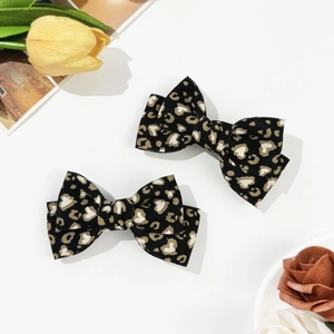 Detailed view of leopard print bow hair clips with soft fabric texture and heart patterns