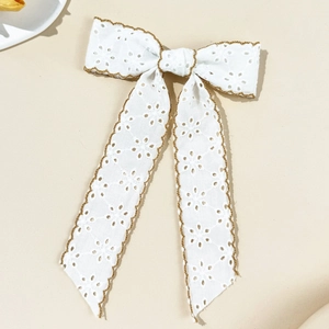 Close-up of vintage white lace bow hair clip with embroidered hollow edges and long streamers