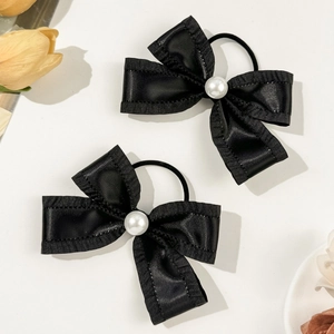 Detail view of black satin bow hair ties with white pearl center and elastic bands