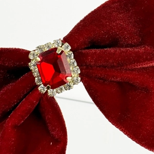 Macro detail of red velvet bow hair clip with ruby gemstone and rhinestone embellishment