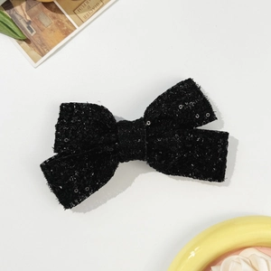 Detailed macro view of a black sequined tweed bow hair clip with vintage texture