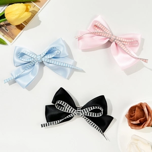 Three elegant checkered bow hair clips in pink blue and black on a minimalist background