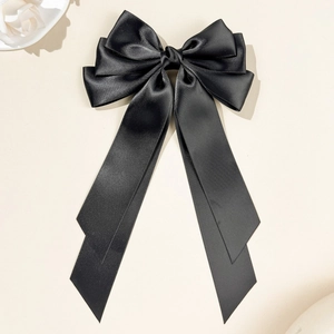 Detail of elegant black satin triple-layer bow hair clip with long ribbons and smooth texture
