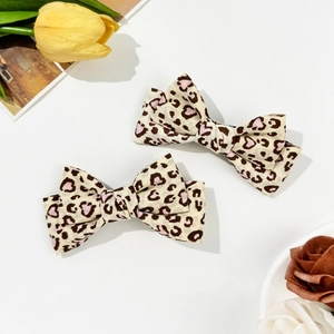 Pair of beige leopard print heart bow hair clips with soft fabric texture for girls