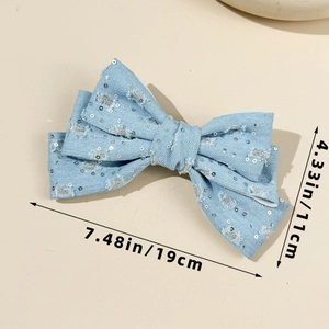 Detail of light blue denim bow hair clip with silver sequins and frayed edges, 19cm in size