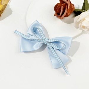 Detail of light blue layered bow hair clip with satin fabric and striped ribbon texture
