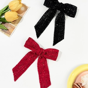 Detail of red and black sequin bow hair clips with elegant long ribbons on white surface