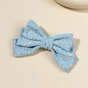 Detail of light blue denim bow hair clip with silver sequins and frayed texture