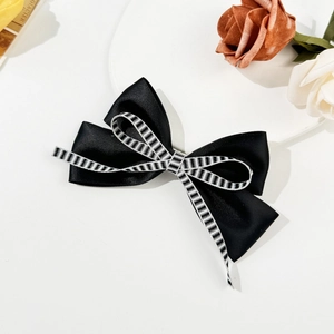 Detail view of black satin bow hair clip with black and white striped ribbon texture