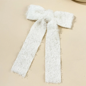Detail of white teddy fleece bow hair clip featuring soft textured plush fabric and long ribbons