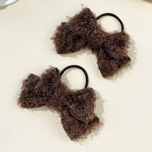 Detail of plush dark brown bow hair ties with soft curly faux fur texture and black elastics