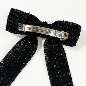 Detail of the silver metal clip back on a black tweed bow hairpin with sequins