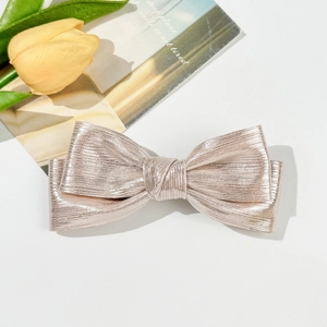 Détail du nœud à cheveux doré champagne avec tissu métallique texturé et effet brillant