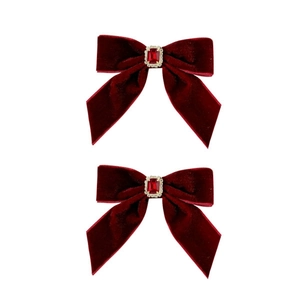 Pair of red velvet bow hair clips with ruby gemstone center on a white background