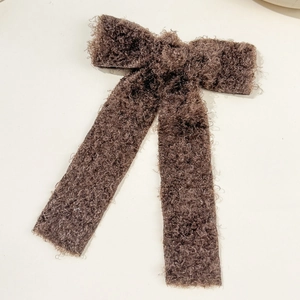 Detail of dark brown bouclé teddy plush bow hair clip with elegant long ribbons
