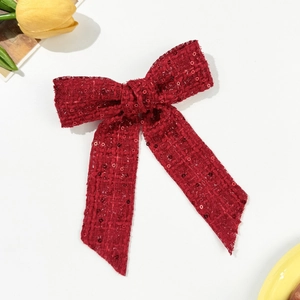 Detail of red sequined tweed bow hair clip with textured fabric for elegant styling