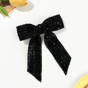 Close-up of a black sequined bow hair clip with long ribbons on a white background