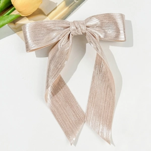 Détail d'une pince à cheveux à nœud plissé rose champagne élégante avec de longs rubans