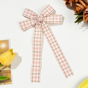 Pink and white plaid bow hair clip with long ribbons on a clean white surface