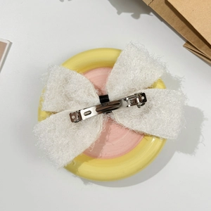 Détail d'une grande pince à cheveux en peluche blanche avec fermoir crocodile en métal