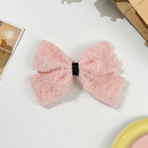 Détail de la pince à cheveux noeud rose en peluche avec ruban noir sur fond rétro