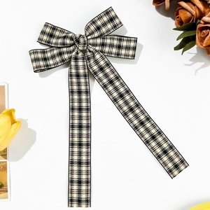 Close-up of vintage plaid bow hair clip with long ribbons and elegant checkered fabric