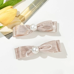 Detailed macro view of pink bow hair clips with metallic thread and white pearls