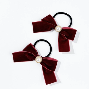 Détail de deux chouchous nœuds en velours bordeaux avec perle et élastique noir résistant
