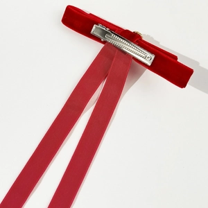 Detail of red velvet bow hair clip showing silver metal alligator clip and long ribbons