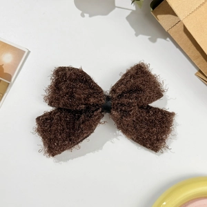 Gros plan d'une pince à cheveux nœud en polaire marron sur fond esthétique épuré
