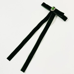 Close-up of deep green velvet bow with emerald-cut gemstone and long ribbons