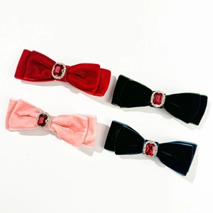 Close-up of velvet bow hair clips with ruby centers in red, pink, green and navy blue