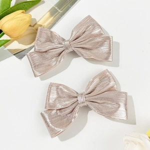 Detailed macro view of two pink glitter bow hair clips with textured metallic finish