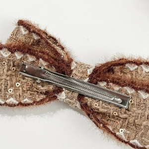 Detail showing the brown tweed bow hair clip with gold sequins and metal duckbill clip