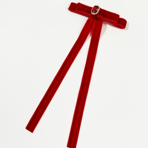 Detailed macro view of dark red velvet bow hair clip with oval ruby gemstone and long ribbons
