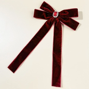Détail d'un nœud en velours rouge avec un rubis central et des cristaux étincelants