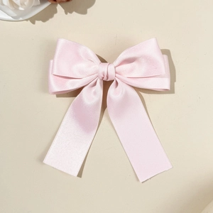 Détail d'une élégante pince à cheveux avec nœud en satin rose et longs rubans soyeux