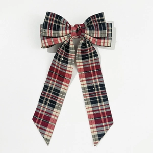 Detail of red plaid bow hair clip with gold sequins and elegant long ribbon tails