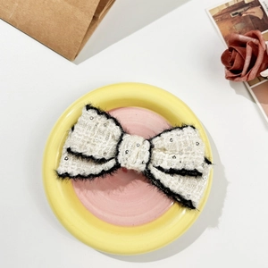 Close-up of elegant tweed bow hair clip with sequins and soft black velvet trim edges