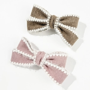 Set of two knitted bow hair clips in pink and brown with white plush wavy edges