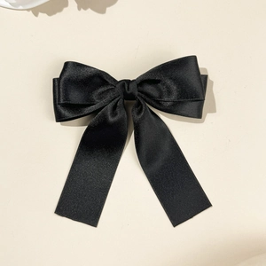 Gros plan sur le nœud papillon en satin noir montrant la texture soie et le double ruban