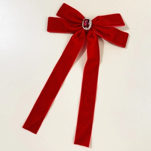 Détail du nœud en velours rouge avec rubis ovale central et halo de strass étincelants