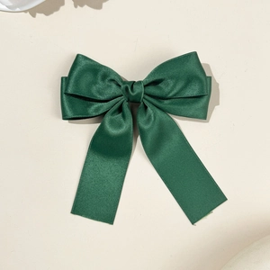 Détail de la pince à cheveux nœud en satin vert foncé avec texture soyeuse élégante