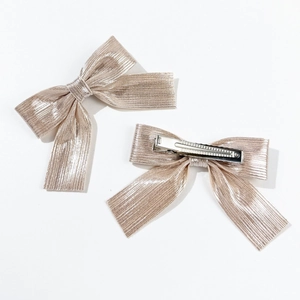 Close-up of pink champagne metallic fabric bow hair clips with metal alligator grip