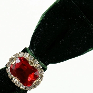 Macro detail of dark green velvet bow hair clip with luxury red faceted gemstone