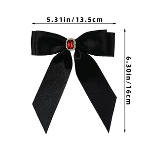 Détail d'un nœud papillon en satin noir avec gemme rouge et strass blancs sur pince à cheveux