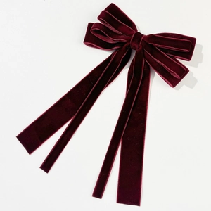 Close-up of elegant burgundy velvet bow hair clip with long streamers and soft texture