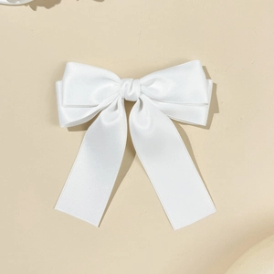 Détail d'une pince à cheveux en satin blanc avec double nœud et longs rubans élégants