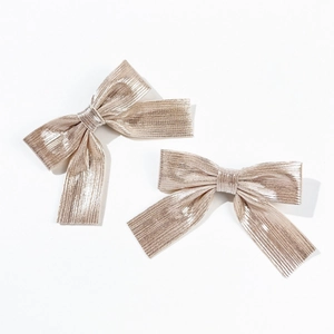 Pair of champagne gold pleated bow hair clips with elegant long tails on white background