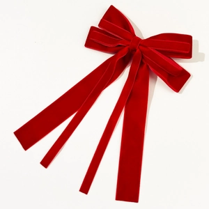 Macro detail of large red velvet bow hair clip with elegant long ribbons for hair